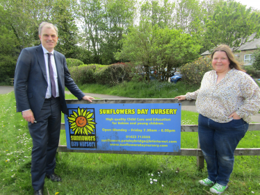 Julian and Heather standing next to the Sunflowers Day Nursery sign